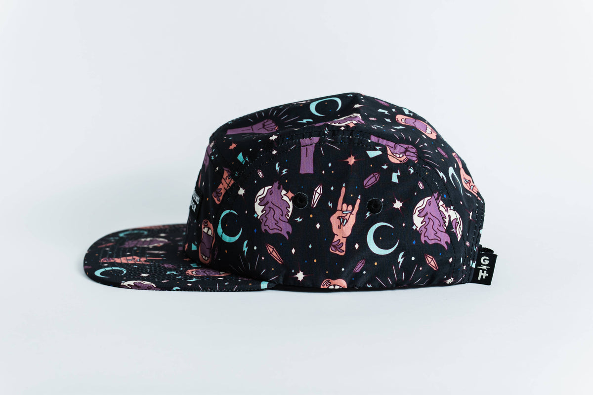 The women-owned Gritty Habits x Ground Keeper: Howl Collection 5-Panel Hat is a black flat-brim hat featuring colorful moons, stars, mystical symbols, and gesturing hands in purple, blue, and pink on a light background.