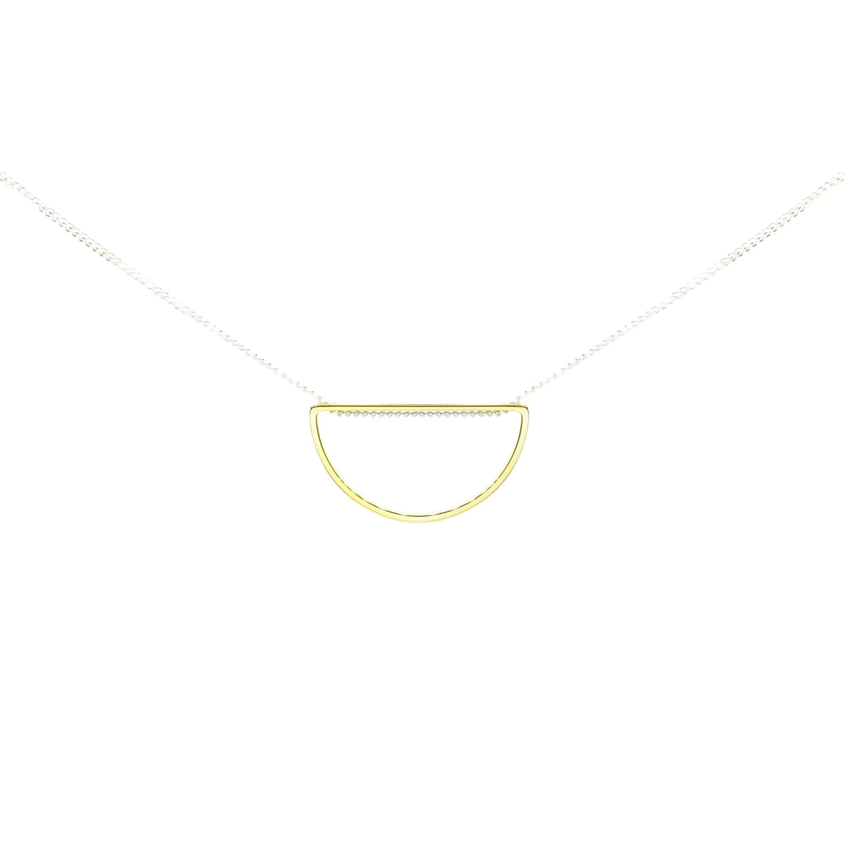 The Afternoon Light Necklace is a handmade mixed-metal piece featuring a thin silver chain and a small, open half-circle gold-plated brass pendant, beautifully displayed against a white background.