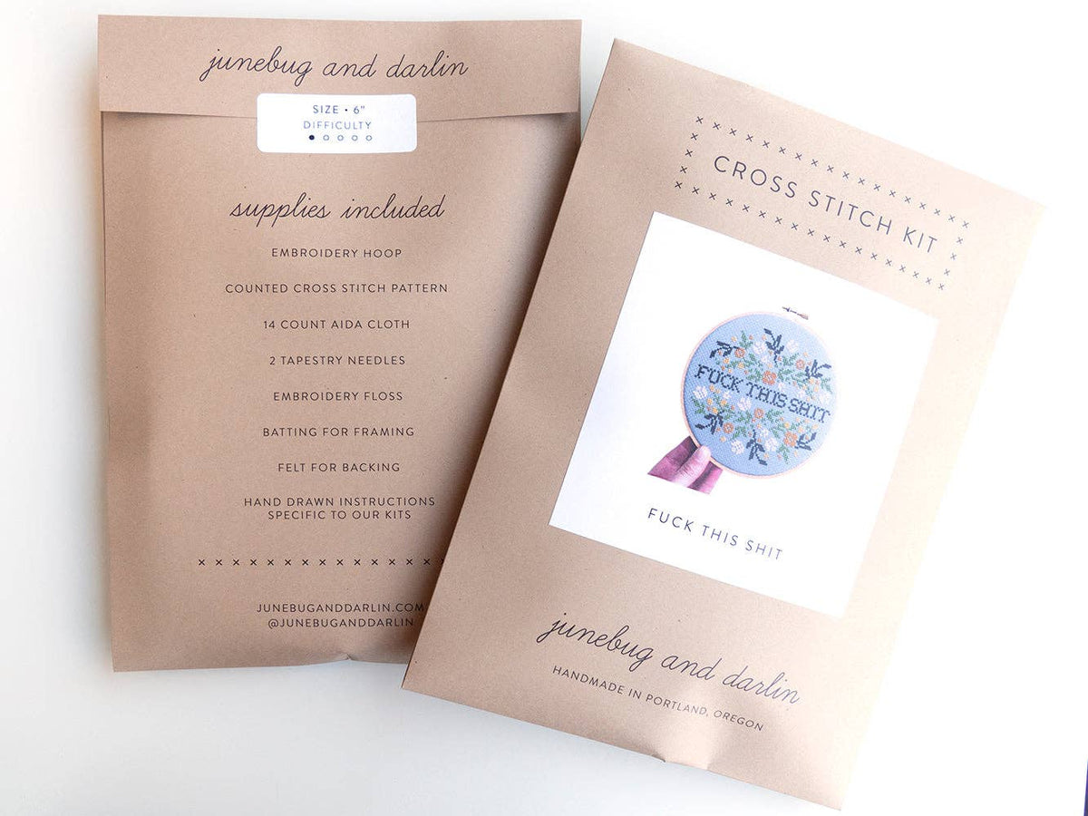 Two brown paper packages labeled junebug and darlin. One holds the Fuck This Shit Cross Stitch Kit with floral designs; the other lists included supplies and beginner embroidery details. Handmade Portland craftsmanship stands out.