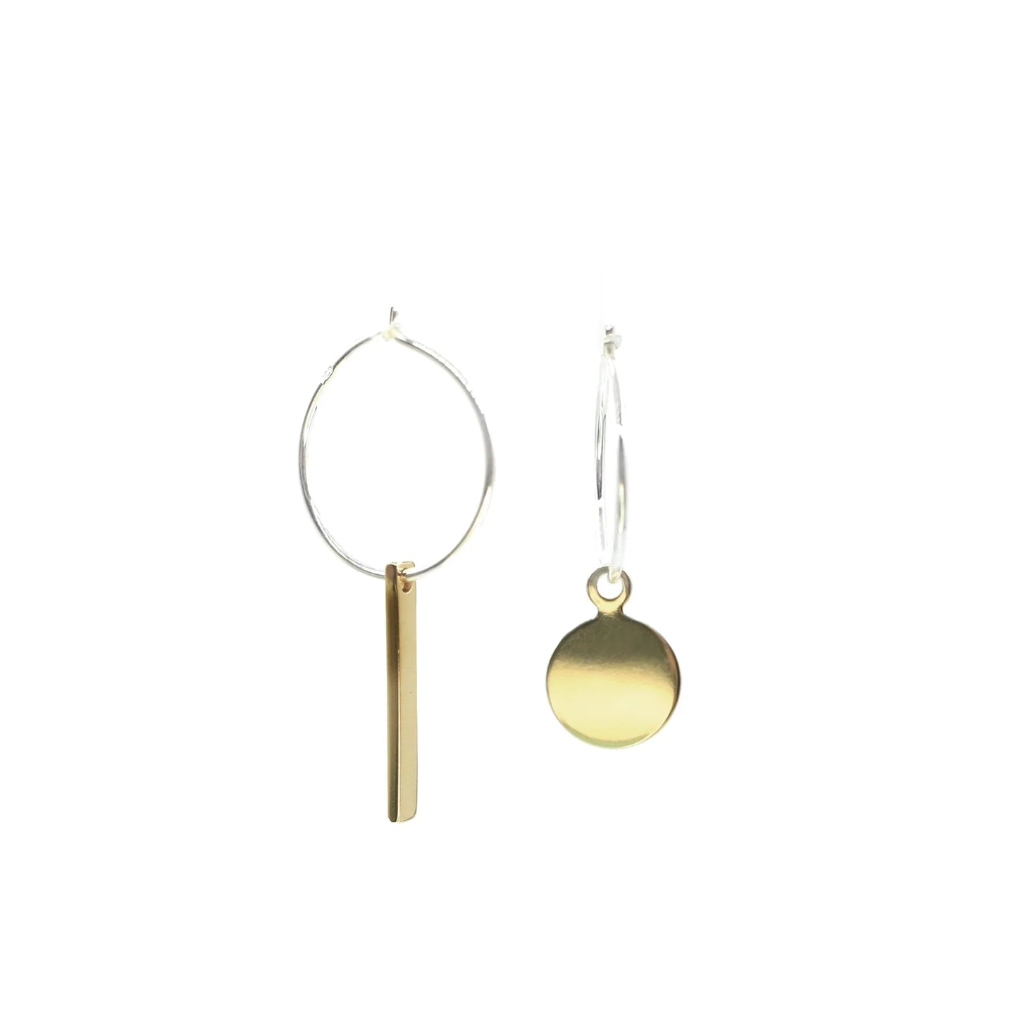 The Akabeko Earrings are a mismatched handmade pair crafted from brass and sterling silver: one earring features a vertical gold bar charm, the other a round gold disc charm, both on sleek silver hoops.