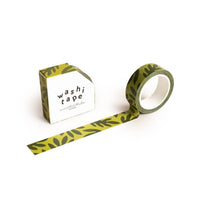 The Lush Leaves Pattern Washi Tape, featuring a dark green plant motif, is partially unrolled beside its eco-friendly box labeled “washi tape” in bold black text on a white background.