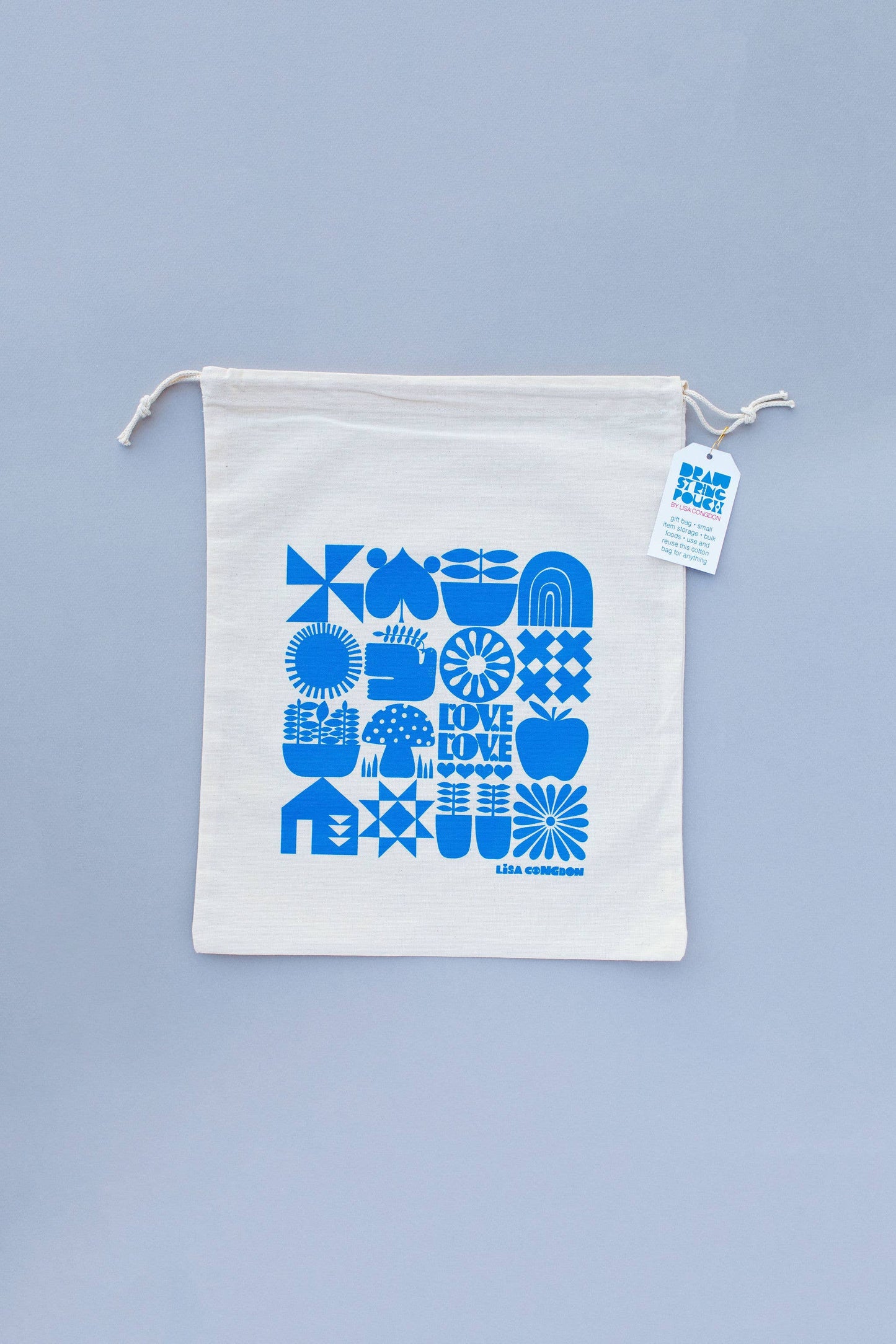 The Large Cotton Drawstring Pouch features blue geometric and abstract prints, a white tag with matching blue designs, and is displayed flat on a light gray surface. Ideal for reusable gift wrapping or as a travel bag.