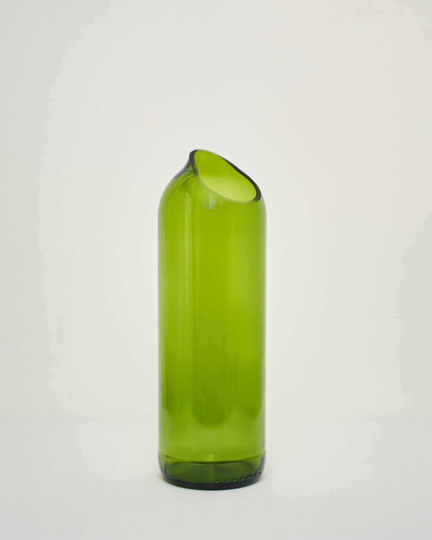 The Kikuba Upcycled Vase is a tall, green glass vase with a rounded body and angled, asymmetrical opening, handcrafted in Zanzibar and shown on a plain white background.