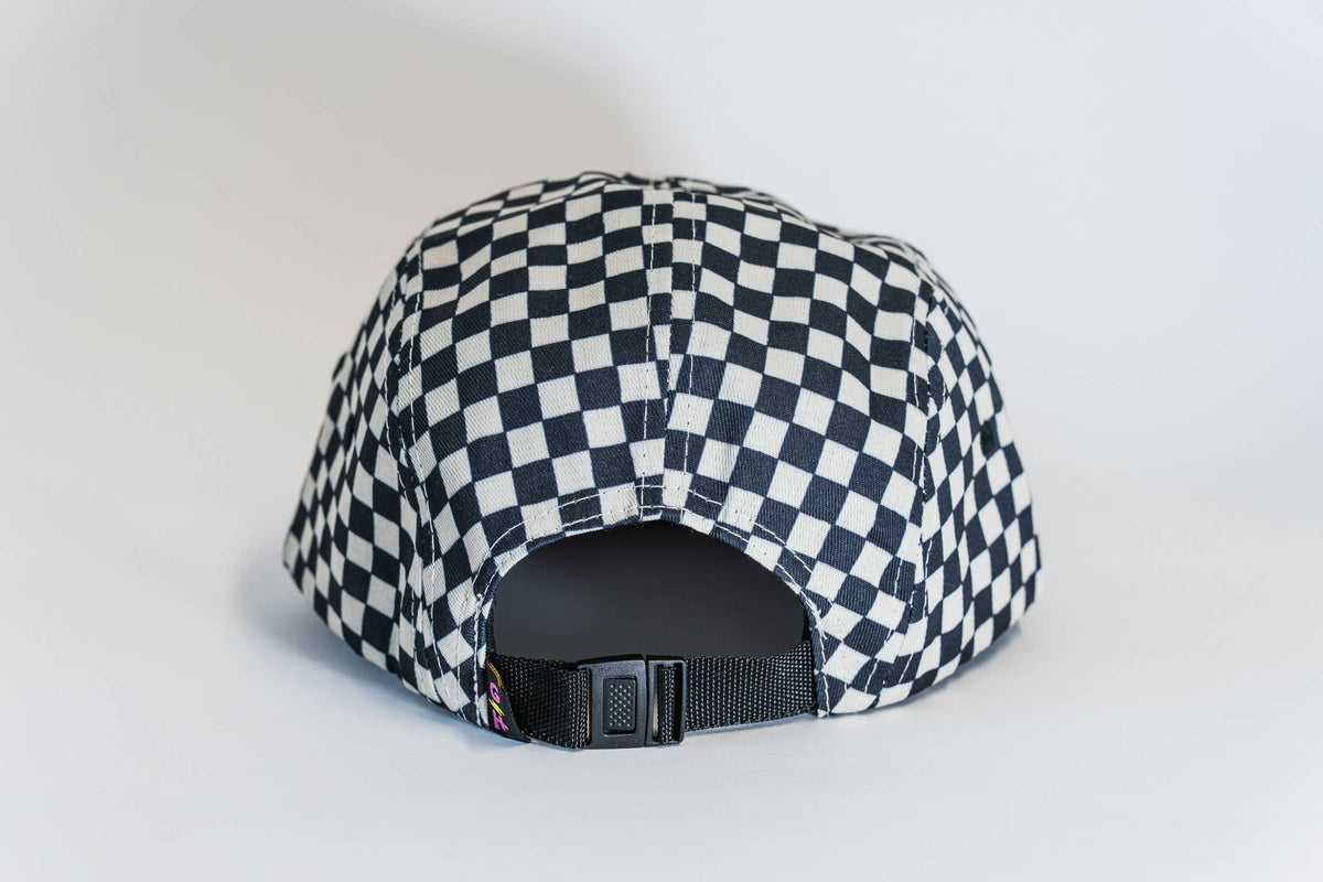 The Steezy Checkered 5-Panel Hat is shown from the back, featuring a black and white checkered design, a plastic adjustable strap, and a curved shape—crafted by a women-owned small business.