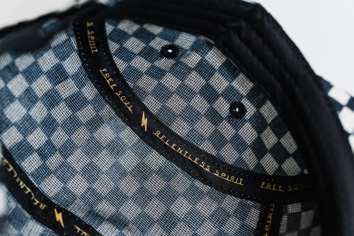 Close-up of the Steezy Checkered 5-Panel Hat’s interior, showing blue and white plaid fabric with black bands displaying RELENTLESS SPIRIT and FREE SOUL in gold, designed by a women-owned small business.