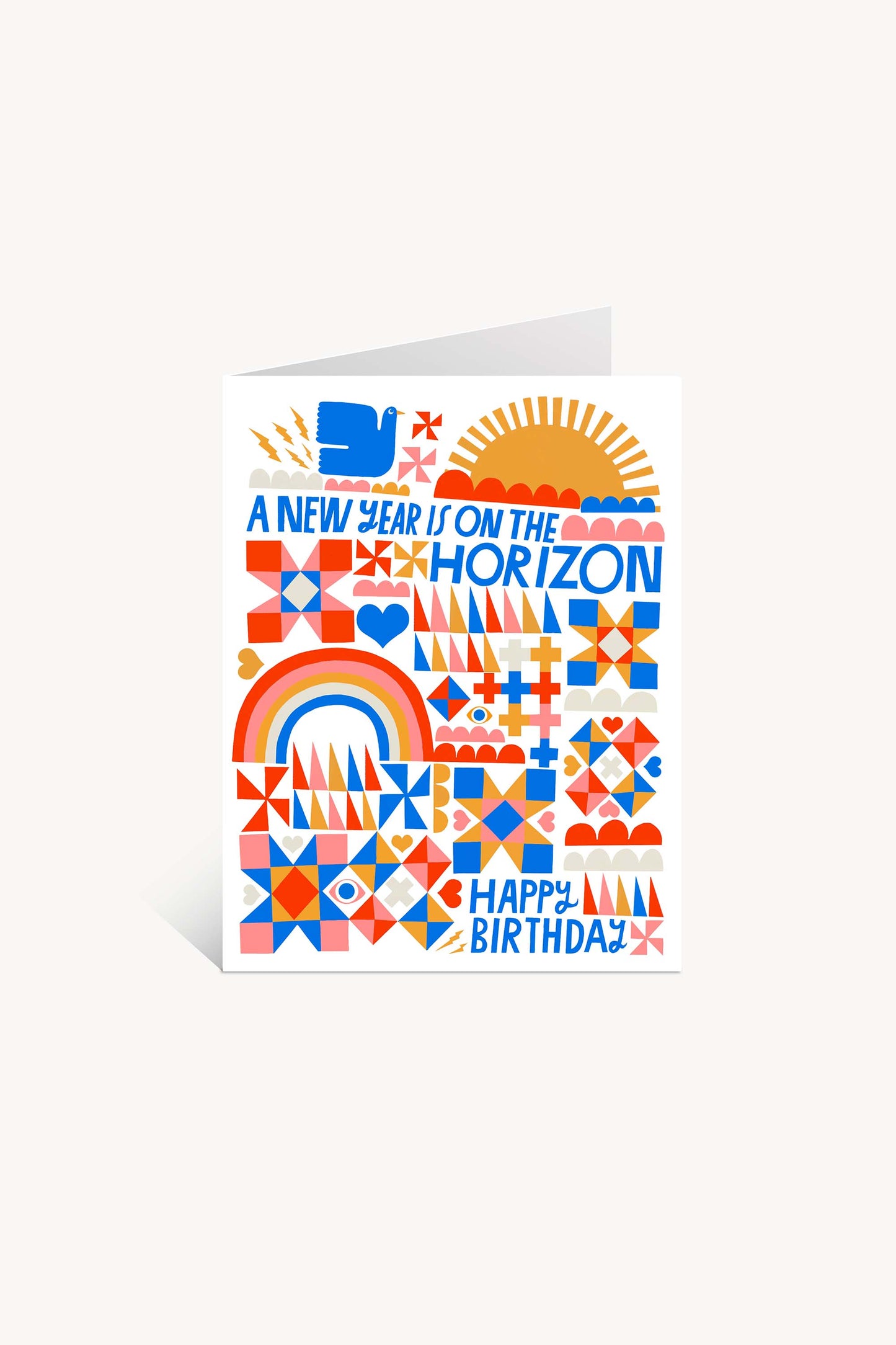 A New Year is on the Horizon Greeting Card features bold geometric patterns, rainbows, hearts, and suns in orange, red, and blue. Printed on FSC-certified paper. Text reads: A NEW YEAR IS ON THE HORIZON (top), HAPPY BIRTHDAY! (bottom).