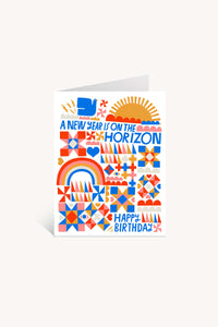 A New Year is on the Horizon Greeting Card features bold geometric patterns, rainbows, hearts, and suns in orange, red, and blue. Printed on FSC-certified paper. Text reads: A NEW YEAR IS ON THE HORIZON (top), HAPPY BIRTHDAY! (bottom).