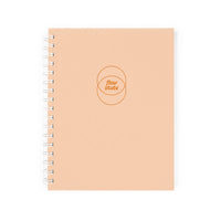 A peach-colored spiral notebook, the “Flow State Guided Journal,” displays “flow state” within two overlapping circles on the cover—ideal for documenting your creative process—pictured on a white background.