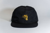 The Fearless 5-Panel Hat is a black cap with an embroidered yellow cobra, mouth open and tongue out, on the front. Displayed on a white background, it's part of the Gritty Habits collection.