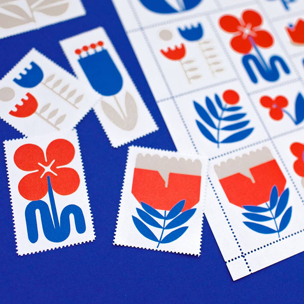 Colorful, limited-edition Poster Stamp Series 3 | March Flowers by Lisa Congdon features bold red, blue, and gray floral designs scattered on a bright blue surface. Some stamps are separated; others remain attached in sheets.
