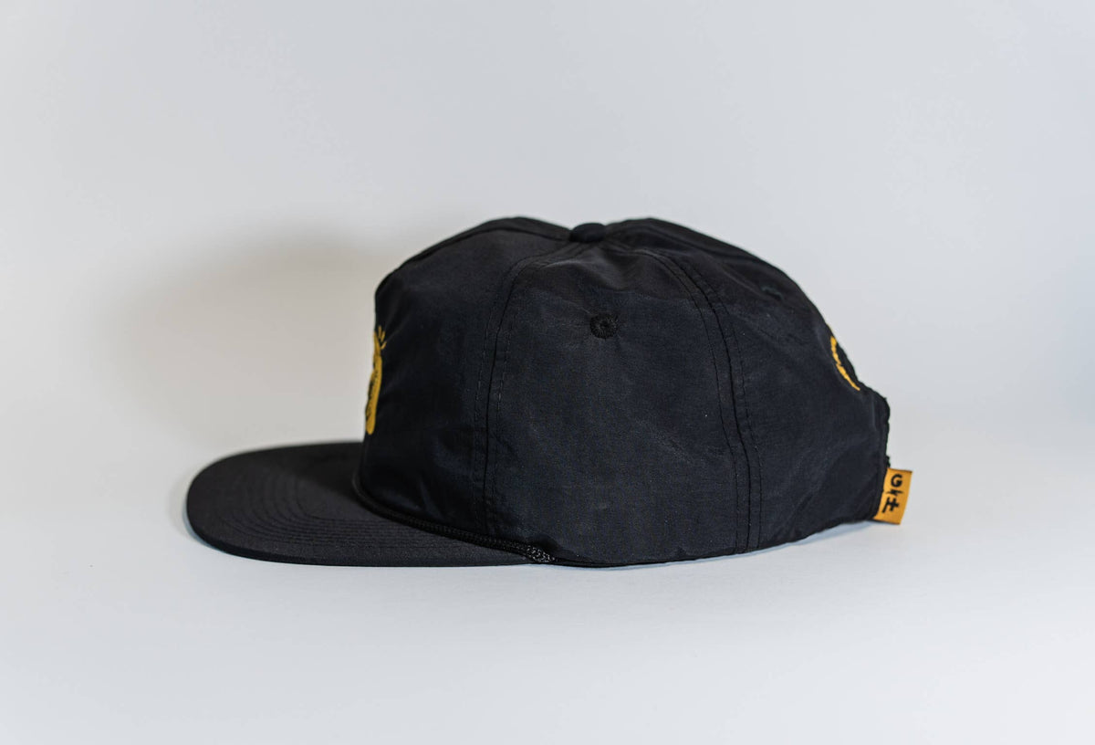 The Fearless 5-Panel Hat is black, shown from the side with a curved brim and a small yellow Gritty Habits tag with text on the back. The background is plain white.