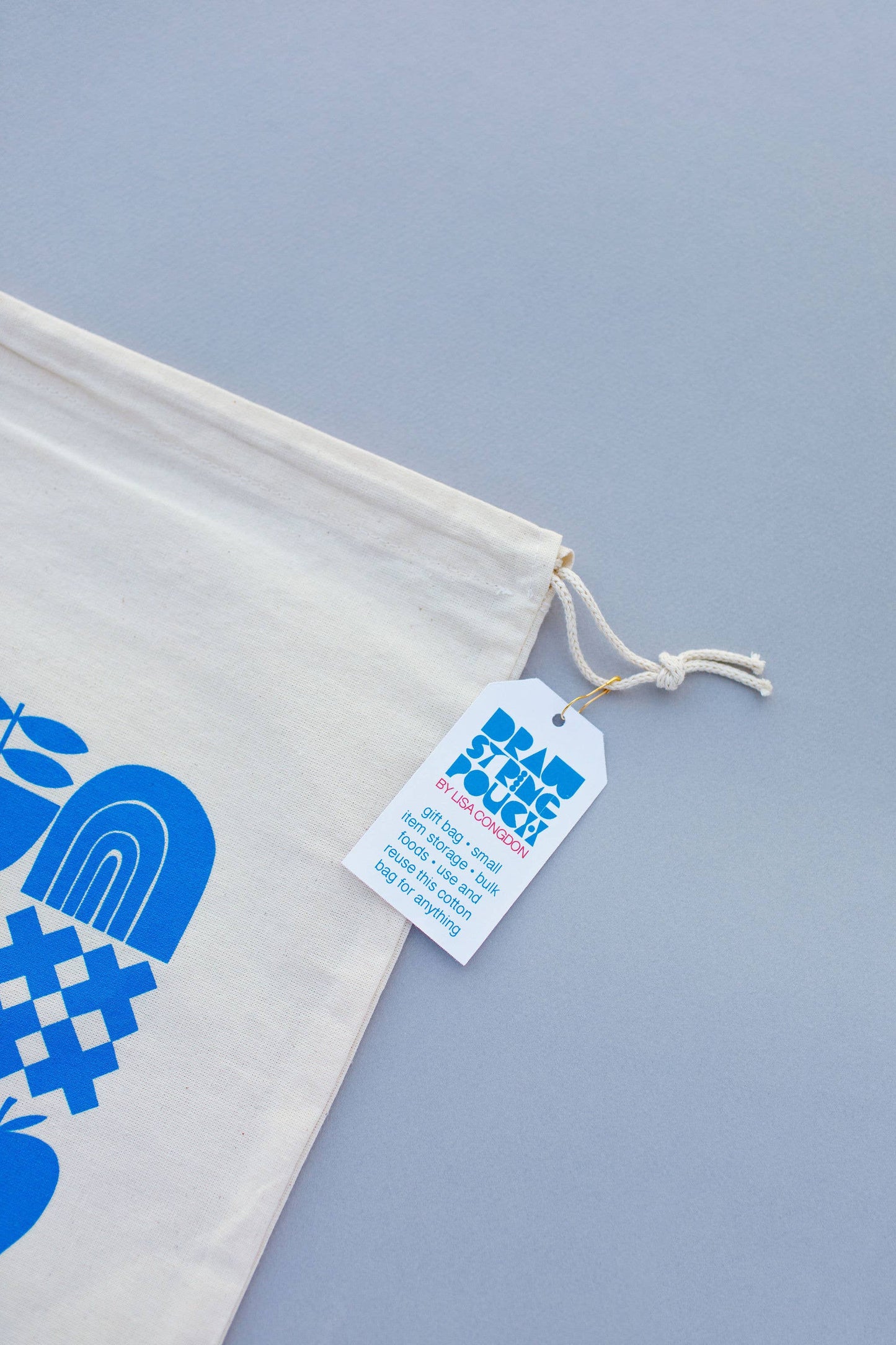 The Large Cotton Drawstring Pouch features a blue abstract design on cotton and is displayed on a light gray background. A white tag with blue and red text highlights Plastic Free and Gift Bag Concept—ideal for reusable gift wrap.