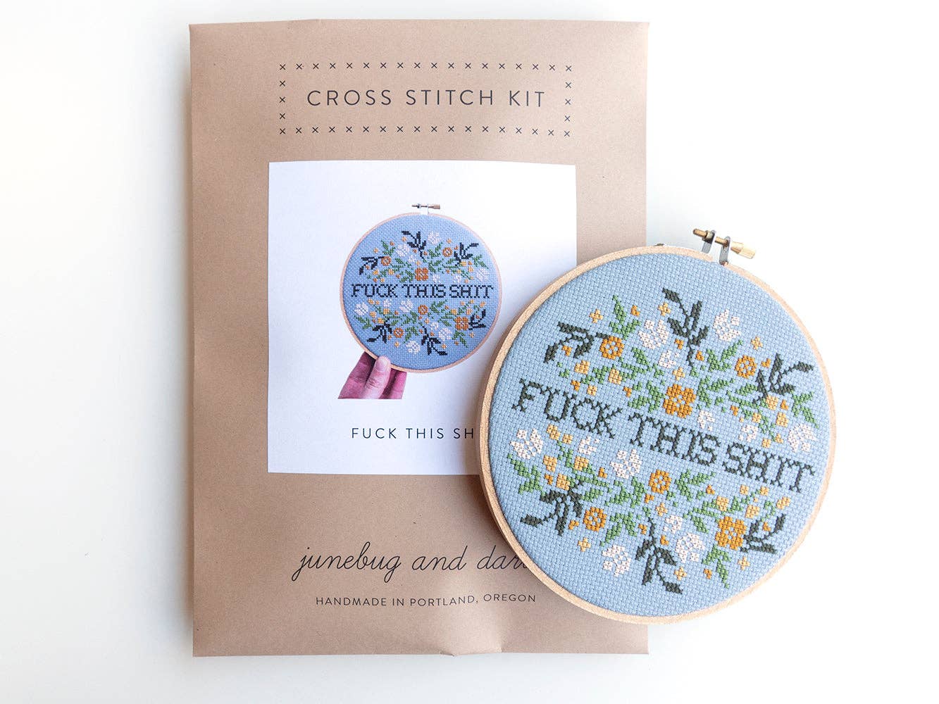 The Fuck This Shit Cross Stitch Kit is a beginner-friendly floral embroidery set with “FUCK THIS SHIT” in bold black letters and colorful flowers, packaged in a handmade Portland pattern.